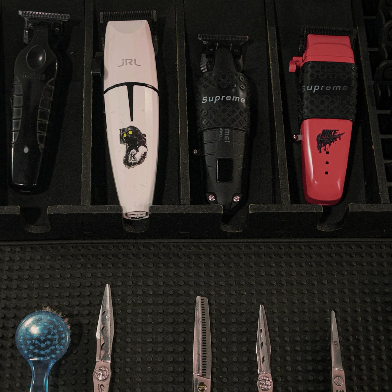 Máquinas de corte e tesouras profissionais organizadas na bancada da The Kings Barbearia